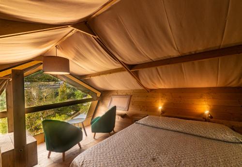 a bedroom with a bed and chairs in a room at Delle Rose Camping & Glamping Village in Isolabona