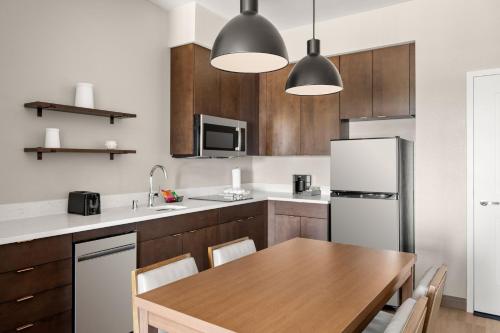a kitchen with a wooden table and a white refrigerator at Residence Inn by Marriott Milwaukee Brookfield at Poplar Creek in Brookfield