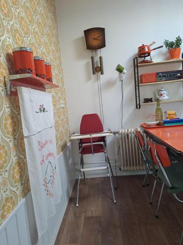 a dining room with a red chair and a table at B&B Ut Kantuurke in Neer
