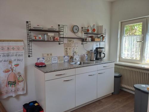 a kitchen with white cabinets and a sink at B&B Ut Kantuurke in Neer