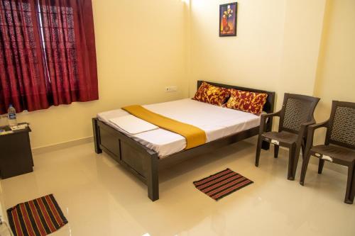 a small bedroom with a bed and two chairs at SKS Residency in Mahabalipuram