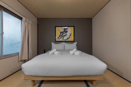 a bedroom with a large white bed and a window at Shiki Homes HIKARI in Kyoto