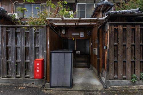 an entrance to a wooden fence with a trash can at Shiki Homes HIKARI in Kyoto