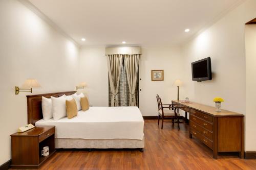a hotel room with a bed and a desk and a television at Ambassador, New Delhi - IHCL SeleQtions in New Delhi
