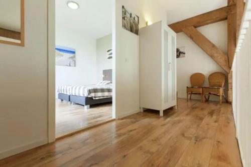 a room with a bed and a bedroom with wooden floors at Huis in de polder in Kamperland