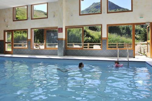 2 personnes nagent dans une piscine dans l'établissement Appartement refait à neuf à Valmeinier, à Valmeinier