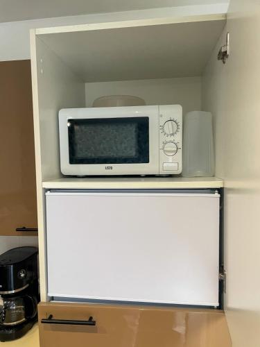 a microwave sitting on top of a white refrigerator at Au Puits Saint Josse - Centre Historique - WIFI in Arras
