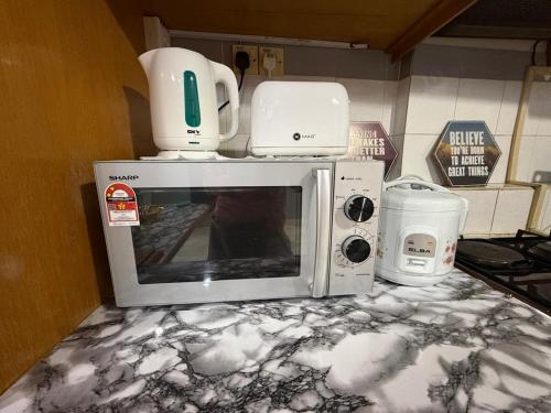a microwave with a white appliance sitting on top of it at Bayu Beach Resort Port Dickson Santai PD Homestay 2 Bedroom Apartment in Port Dickson