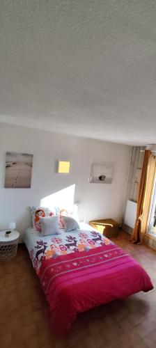 une chambre avec un grand lit avec une couverture rose dans l'établissement Appartement Studio T1bis ALOHA avec terrasse en front de mer, à Capbreton