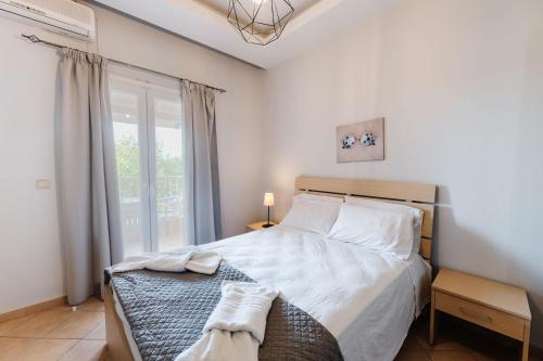 a bedroom with a bed with white sheets and a window at Spyridoula Resort in Corfu in Gouvia