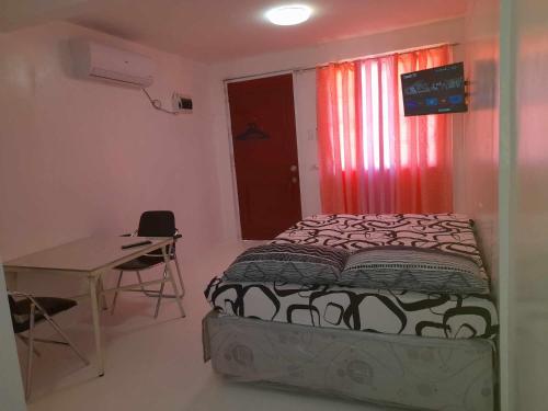 a bedroom with a bed and a table and a window at FJM Transient in Tarlac