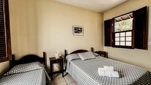 a bedroom with two beds and a window at Pousada Villa Aman in Paraty