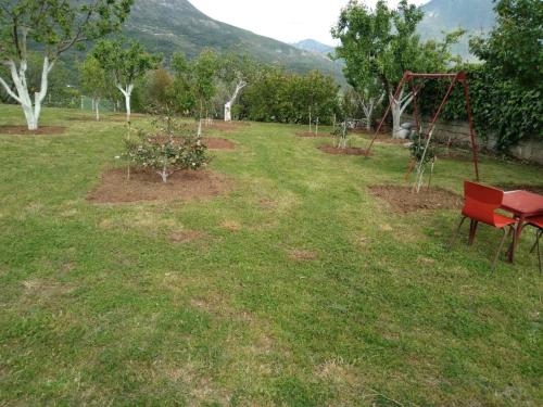 a park with a red bench and a swing at Liam rooms in Tepelena Center in Tepelenë