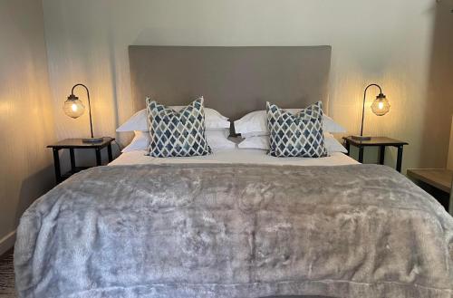 een slaapkamer met een groot bed met twee lampen bij De Gunst Guest Farm in Malmesbury