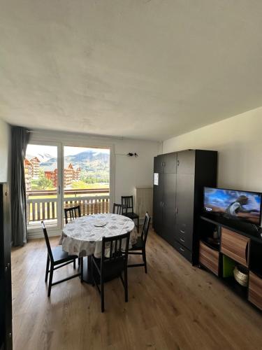 une salle à manger avec une table avec des chaises et une télévision dans l'établissement Studio 4 à 6 personnes, à Saint-Étienne-en-Dévoluy