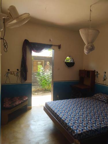 a bedroom with a bed in a room with a window at Chez Yaya, chambre bleue in Oussouye