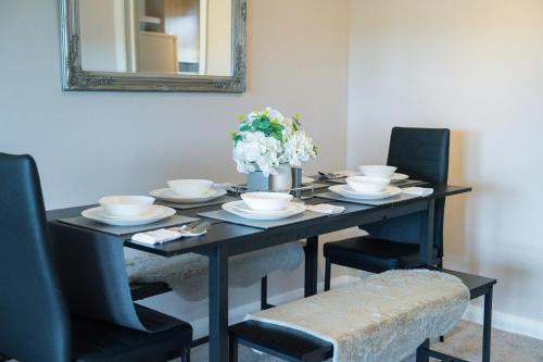 a black dining room table with chairs and a mirror at Trendy Central Apartment with Free Parking - Perfect for Contractors and Families in Canterbury