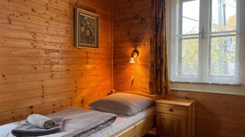 a room with two beds in a wooden room with a window at Drevenica u Porubäna in Jakubovany