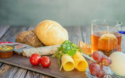 a cutting board with bread and vegetables and a glass of juice at Unieke Bed en Breakfast met historisch verhaal in Ferwert De K roon van Marijn in Ferwerd