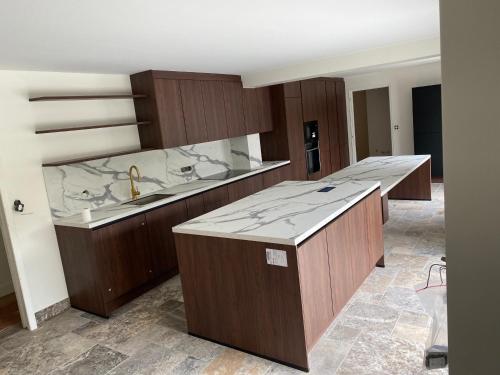 a large kitchen with wooden cabinets and a sink at Maison familiale LA ROCHELLE in LʼHoumeau