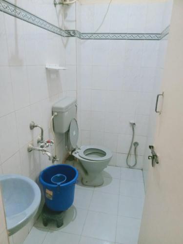 a bathroom with a toilet and a blue bucket at Royal Guest inn HSR Layout in Bangalore