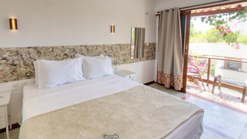 a bedroom with a large white bed with a window at Pousada Morada do Sol in Camocim