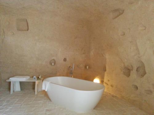 a bath tub in a bathroom with a stone wall at Le Dimore Dell' Idris in Matera