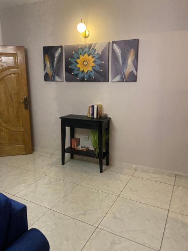 ドゥアラにある3T Houseのテーブルと壁に3枚の絵が掛かっている部屋