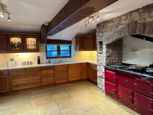 a kitchen with wooden cabinets and a stone wall at The Old Dairy in Chepstow