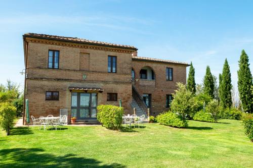 a large brick building with tables and chairs in a yard at Casavacanze Vesta in Isola d'Arbia