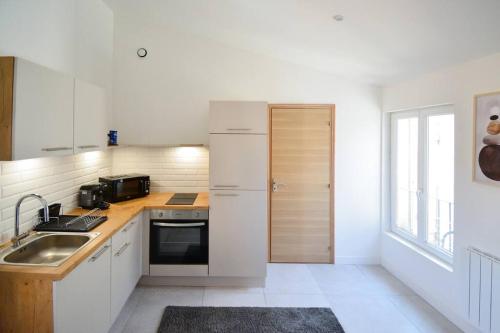 une cuisine blanche avec un évier et une cuisinière dans l'établissement Bazille, gare Saint Roch, à Montpellier