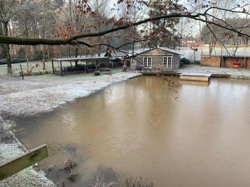 a body of water with a building in the background at Unieke chalet aan het water in Lille
