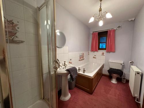Un baño con bañera, lavabo y ducha. en The Old Dairy, en Chepstow