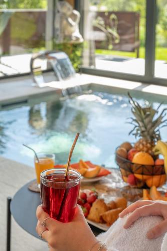 a person holding a drink in front of a tub of fruit at Chalet Soleil Bœuf et Spa de l'adouss in Saint-Jean-Saint-Nicolas