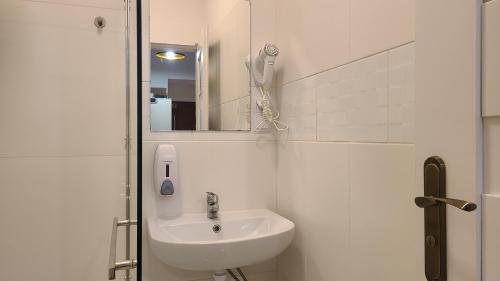 Un baño blanco con lavabo y espejo. en Lorf Hostel&Apartments, en Cracovia