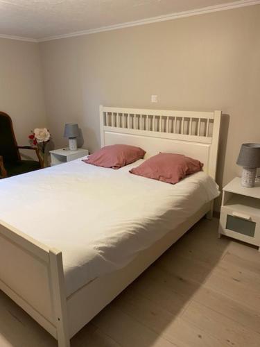 - une chambre avec un lit blanc et 2 oreillers roses dans l'établissement Au calme, à Villersérine