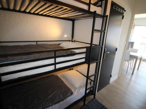 two bunk beds in a room with a table at Studio cabine rénové, 4 couchages, pied des pistes, parking, balcon sud - FR-1-297-160 in Auris