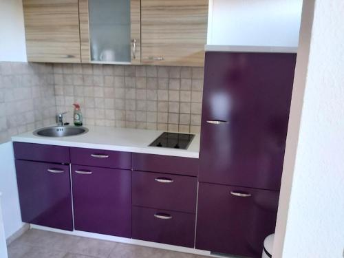 a kitchen with purple cabinets and a sink at Apartment in Delitzsch