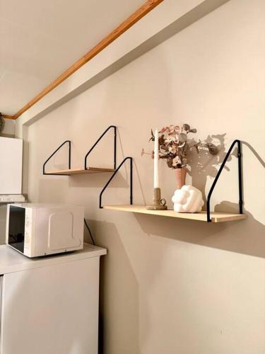 a shelf with flowers and a microwave on a wall at Mye for pengene, sentralt i Narvik! in Narvik