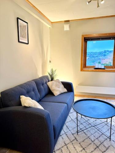 a living room with a blue couch and a glass table at Mye for pengene, sentralt i Narvik! in Narvik