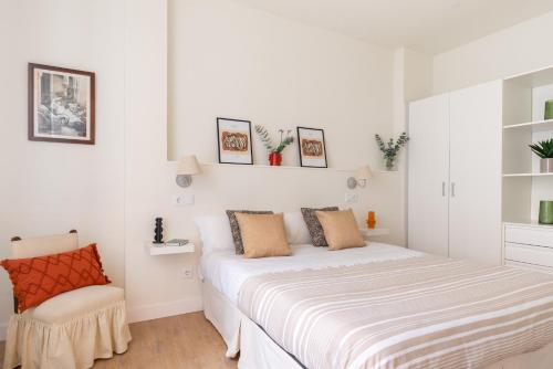 a white bedroom with a bed and a chair at Sweet Home Santander in Santander