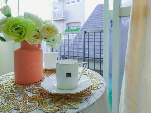 a table with a coffee cup and a vase with flowers at 羊の宿地铁口徒步六分钟电车八分钟到梅田商圈 in Osaka