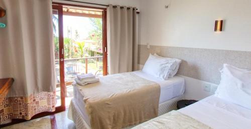 a hotel room with two beds and a window at Pousada Morada do Sol in Camocim