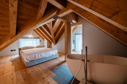a attic bedroom with a bed and a bath tub at DALANIA MOUNTAIN APARTMENTS in Ponte di Legno