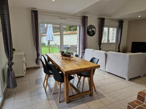 un salon avec une table et des chaises en bois dans l'établissement Maison de charme avec jardin au bord de l'Eure, à Le Vaudreuil