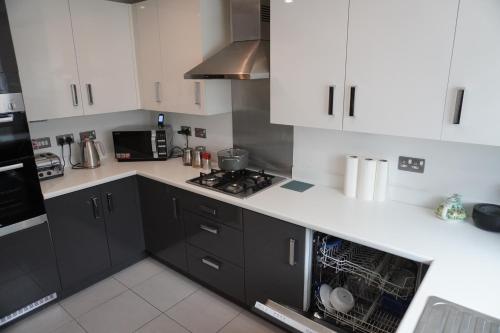 a kitchen with white cabinets and a stove top oven at Luxury Rooms - Pick a Room - Free Parking & Kitchen Access, Near Etihad Stadium, The Coop Live & Piccadilly Station, Manchester in Manchester