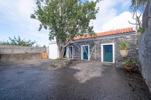 a stone building with a tree in front of it at Casa do Maurício by GALMI in Ponta do Pargo