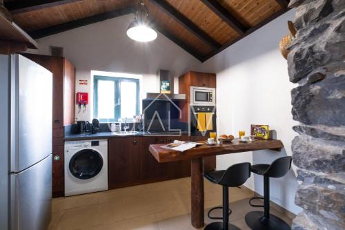 a kitchen with a table and a washer and dryer at Casa do Maurício by GALMI in Ponta do Pargo