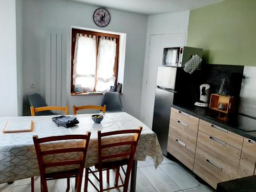 une cuisine avec une table, des chaises et un réfrigérateur dans l'établissement Gîte la maison de Mika, à Saint-Floret