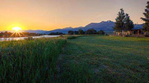 a field of grass with the sunset in the background at Osprey Acres in Emigrant